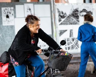 Vue montrant une artiste du spectacle sur un vélo et l'autre dessinant le récit au fusain