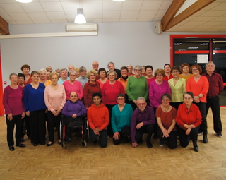 Les membres de la chorale dans la salle polyvalente vétus de couleurs vives