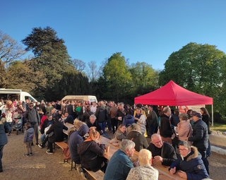 Vue d'un marché de producteurs avec le public attablé devant les stands
