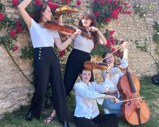 Vue des 4 musiciennes le long d'un mur dans un parc avec leurs instruments