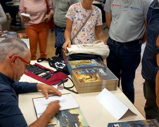 Vue d'un auteur dédicassant son livre lors du salon 2025