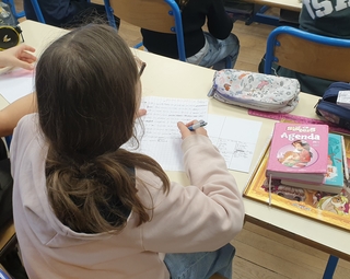 Vue d'une élève écrivant sur son cahier lors des ateliers d'écriture de Souviens-toi du futur