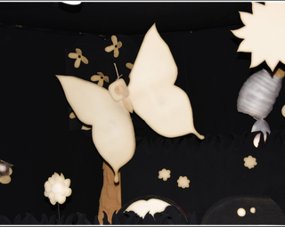 Vue du décor du spectacle comportant un papillon blanc sur un fond noir