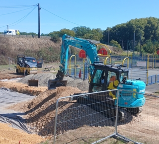 Vue de deux engins de travaux publics qui réalisent le terrassement du futur terrain de basket 3X3