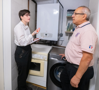 Photo montrant une femme procédant au diagnostic dans la chaufferie d'une maison avec le propriétaire