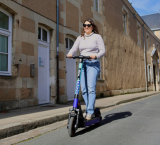 Une jeune femme sur une trotinette dans une rue