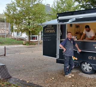 Vue du camion de vente de pizza avec le commerçant à l'intérieur et un client devant