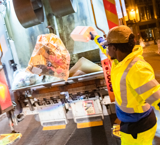 Vue d'un agent de ramassage des déchets à l'arrière d'un camion benne