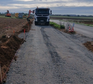 Vue avec des engins de chantier pour la construction d'une piste cyclable aux abords d'une route départementale