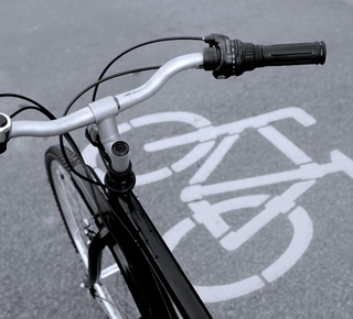 Vue du guidon d'un vélo avec en fond le visuel de la piste cyclable sur la voie