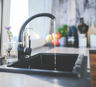 Photo d'un robinet d'un évier de cuisine  avec l'eau qui coule
