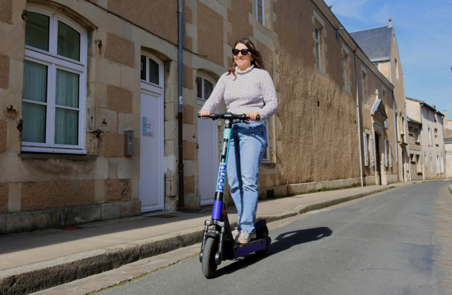 Une jeune femme sur une trotinette dans une rue