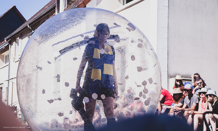 Photo d'une comédienne à l'intérieur d'un gros ballon transparent durant le spectacle