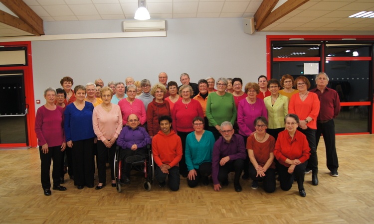 Les membres de la chorale dans la salle polyvalente vétus de couleurs vives