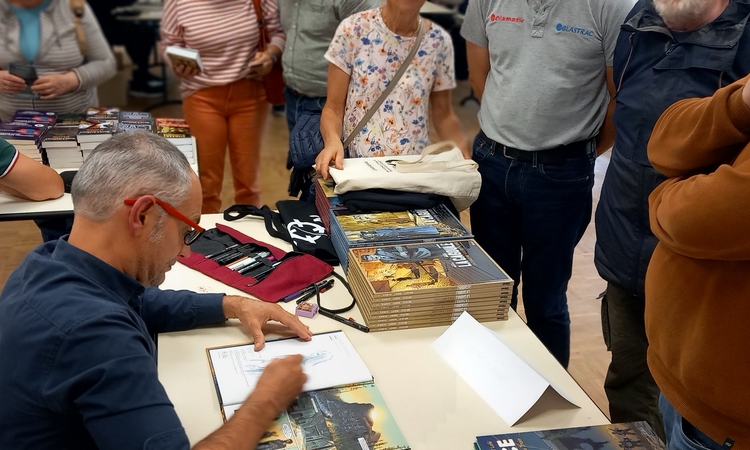Vue d'un auteur dédicassant son livre lors du salon 2025