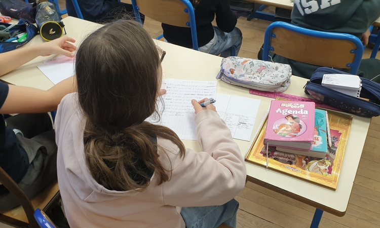 Vue d'une élève écrivant sur son cahier lors des ateliers d'écriture de Souviens-toi du futur