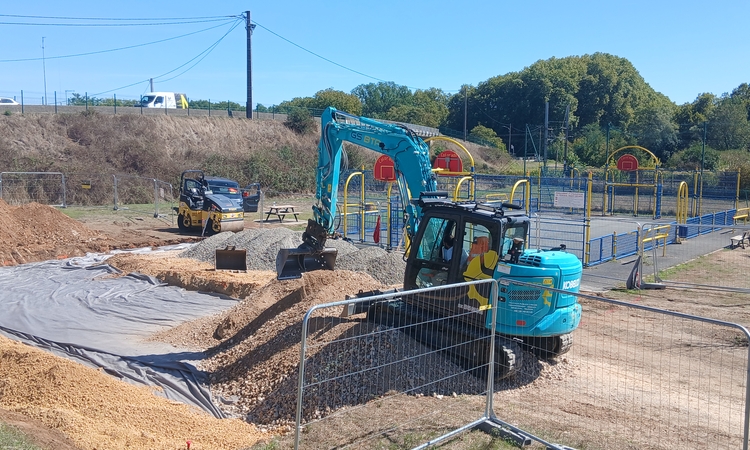 Vue de deux engins de travaux publics qui réalisent le terrassement du futur terrain de basket 3X3