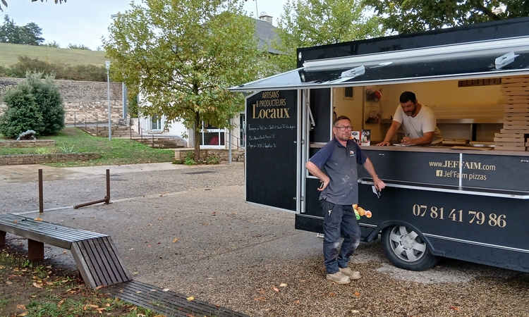 Vue du camion de vente de pizza avec le commerçant à l'intérieur et un client devant