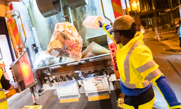 Vue d'un agent de ramassage des déchets à l'arrière d'un camion benne
