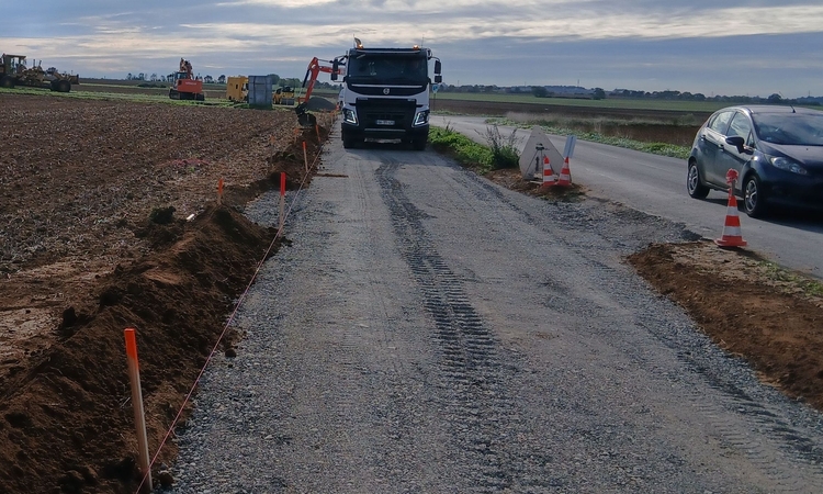 Vue avec des engins de chantier pour la construction d'une piste cyclable aux abords d'une route départementale