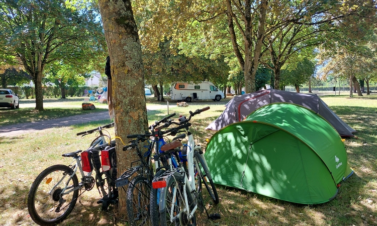 Vue du camping de Dissay avec des tentes et des vélos sous les arbres